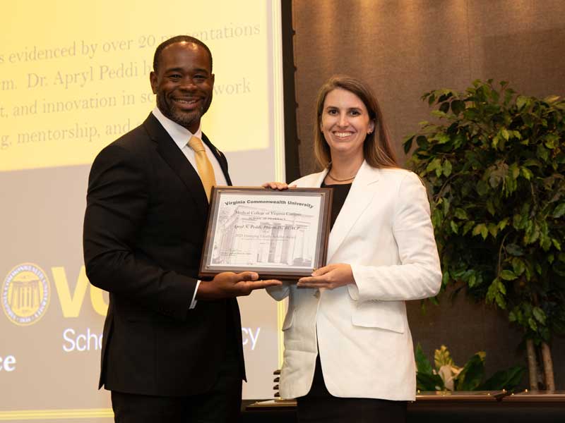 Standing next to Dean K.C. Ogbonna, Apryl Peddi accepts the Emerging Faculty Scholar Award