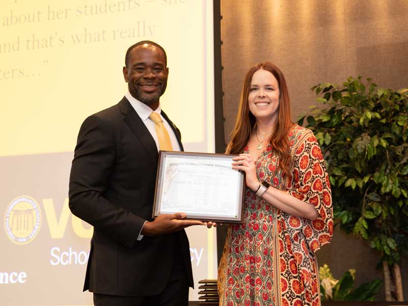 Standing next to Dean K.C. Ogbonna, Cait Gibson accepts the Bertha Rolfe Outstanding Teacher of the Year Award