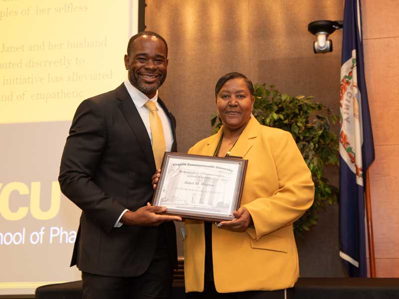 Standing next to Dean K.C. Ogbonna, Janet Wooten accepts the Bertha Rolfe Outstanding Staff Award