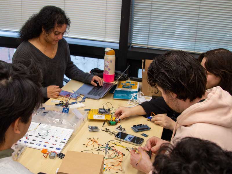 A group of Pharm.D. students work together on a microelectronics project, connecting wiring to a circuit board, in the VCU School of Pharmacy computer lab.